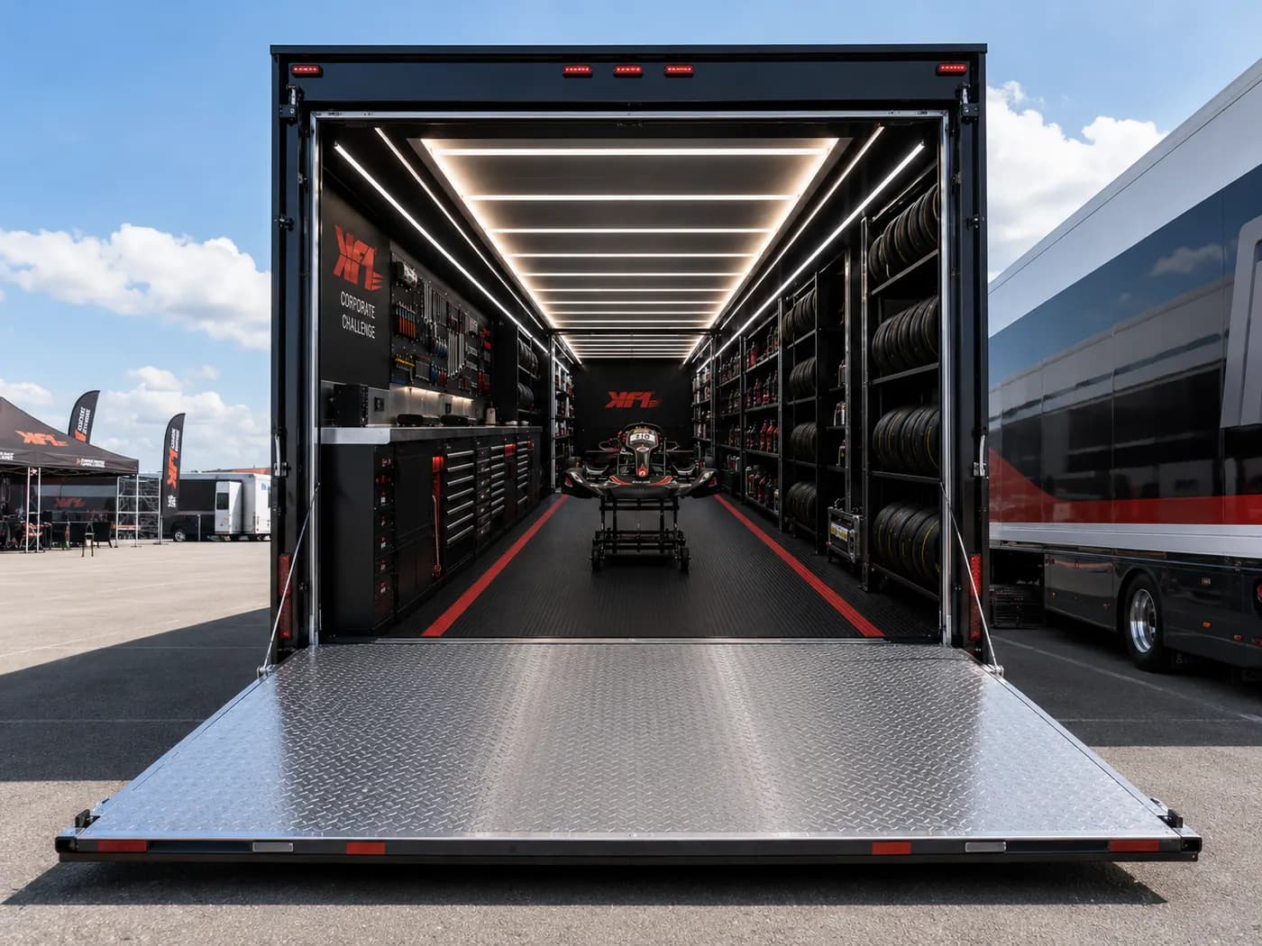 A KF1 mobile workshop trailer with its ramp down in a paddock, tool walls and tyre racks inside